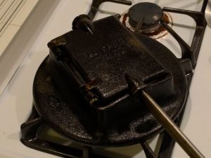 A closed lukken iron hard at work baking a cookie on a stovetop.
