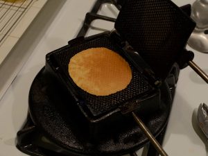 An open lukken iron showing a baked cookie.