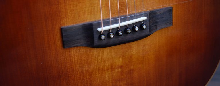 Close up of guitar soundboard showing sunburst coloration and belly bridge.
