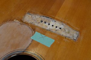 The top of a guitar, under the removed bridge