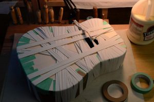 A guitar body, wrapped in twill tape to clamp the new top in place