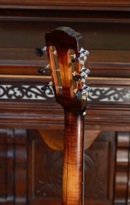 The back of a colored maple guitar neck and headstock